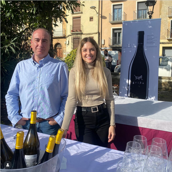 una chica y un chico delante de la mesa con botellas y copas. Están preparados para un evento de vino una chica y un chico delante de la mesa con botellas y copas. Están preparados para un evento de vino